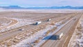 DRONE: Trucks haul cargo along a freeway running across snowy landscape in Utah.
