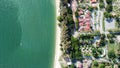 Drone view of the beach with many trees and houses by the turquoise sea in the daytime Royalty Free Stock Photo