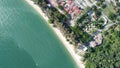 Drone view of the beach with many trees and houses by the turquoise sea in the daytime Royalty Free Stock Photo