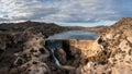 Drone view of the Elche Reservoir and dam wall with waterfall and surrounding semi-desert landscape Royalty Free Stock Photo