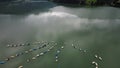 drone view of a lake with a white cloud and a pack of boats in the shape of a flower