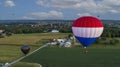 Drone View of Multiple Colorful Hot Air Balloons Landing in Farms Fields, Parking Lots and Homes
