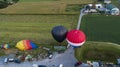 Drone View of Multiple Colorful Hot Air Balloons Landing in Farms Fields, Parking Lots and Homes