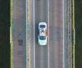 Drone view of a painted white Bentley Unifying spur car driving on a bridge Royalty Free Stock Photo