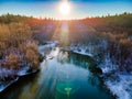 Drone view of a river with a lake on a snowy forest plain during a clear winter morning and bright sunrise Royalty Free Stock Photo