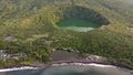 Drone view of Tolire Lake in Indonesia with green forests around and a sea