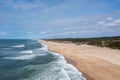 Drone view of a wide empty and endless golden sand beach with high sand dunes and vegetation behind