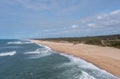 Drone view of a wide empty and endless golden sand beach with high sand dunes and vegetation behind