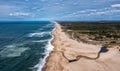 Drone view of a wide endless golden sand beach with a river flowing to the ocean