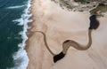 Drone view of a wide endless golden sand beach with a river flowing to the ocean