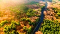 Aerial view of winding forest road in the mountains. Colourful landscape with rural road, trees with yellow leaves at sunset Royalty Free Stock Photo