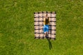 Drone view young woman working on laptop on green grass lying on plaid blanket Royalty Free Stock Photo