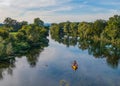 DRONE: Young man paddles canoe along a tranquil river while his friends relax. Royalty Free Stock Photo