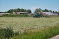 Dronten, the Netherlands June1,2021:Grassland with big tractor mower and rake, grass ready to be ensiled. Farm in