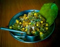 A drooling plate of Indian spicy street snak churmur with a leaf and a spoon