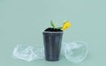 A drooping flower in a plastic cup filled with soil on a green background. The concept of environmental pollution. Land pollution Royalty Free Stock Photo