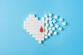 A drop of blood on broken heart made of pure white cubes of sugar isolated on blue background, World diabetes day