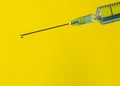 Drop of clear and pure water or medicine on top of a sharp needle of syringe on yellow background with copy space. Concept of Royalty Free Stock Photo