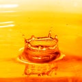 Drop falling into orange water with splash Royalty Free Stock Photo