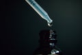 A drop falls from a pipette into a bottle of homeopathic medicine, close-up on a dark background Royalty Free Stock Photo