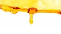 A drop of honey flows down from a wooden spoon.