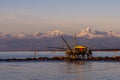 Drop net fishing hut at sunset against the Alps covered with snow, Marina di Pisa, Tuscany, Italy