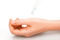 A drop from the pipette drips on a beautiful, well-groomed female hand. Hand skin care product, white background very close-up