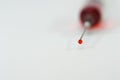 A drop of red medicine in focus coming out of the syringe needle . Royalty Free Stock Photo