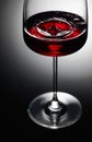 The drop of red wine falls into a wine glass Royalty Free Stock Photo