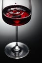 The drop of red wine falls into a wine glass Royalty Free Stock Photo