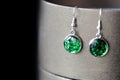 Drop resin earrings with green sparkles on a dark background