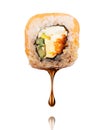 Drop of soy sauce drips from a fresh sushi roll on a white