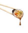 Drop of soy sauce drips from a sushi roll, isolated on white