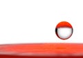 A drop of water in the air above a red surface. Space for text. Royalty Free Stock Photo