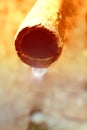 A drop of water hangs from an old water pipe, against the background of a gray concrete wall. Ecological concept of the ancient