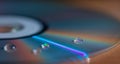 A drop of water on a multi-colored CD - disk. Blurred background, wallpaper. Flat lay, copy space. Royalty Free Stock Photo