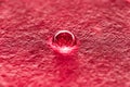 A drop of water on a red relief background, macro background Royalty Free Stock Photo