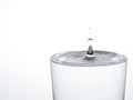 Drop of water, about to make the glass overflow and run over. On white. Royalty Free Stock Photo
