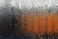 A drop of water on a windowpane. On the background is a gradient of colors from black to white through orange. Romantic and sad ba