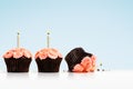 Dropped cupcake in row of cupcakes with candles on blue Royalty Free Stock Photo