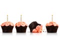 Dropped cupcake in row of cupcakes with candles on white Royalty Free Stock Photo