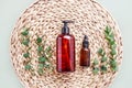 Dropper bottle, eucalyptus branches and dark dispenser bottle of shower gel on rattan background. Beauty and SPA concept