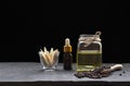 Dropper bottle with herbal essential oil in glass jar and lemon grass slices in little glass with black peppercorns in wooden