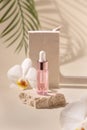 Dropper Bottle on stone near white orchid flowers and palm leaves on light yellow Royalty Free Stock Photo