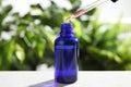 Dropper with essential oil over bottle on white wooden table against blurred Royalty Free Stock Photo