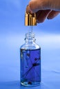 Dropper glass Bottle Mock-Up. Oily drop falls from cosmetic pipette on blue background. Color of the year