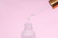 Dropper glass Bottle Mock-Up. Oily drop falls from cosmetic pipette on pink background. Skin care concept Royalty Free Stock Photo