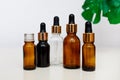 Dropper glass bottles mock up. Cosmetic pipette on white background with tropical leave