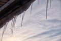 Dropping icicles on a warm spring day hang from the wooden roof of an old house and sparkle in the light on the Sun Royalty Free Stock Photo