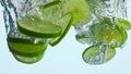 Dropping lime slices water in super slow motion closeup. Pieces citrus splashing Royalty Free Stock Photo